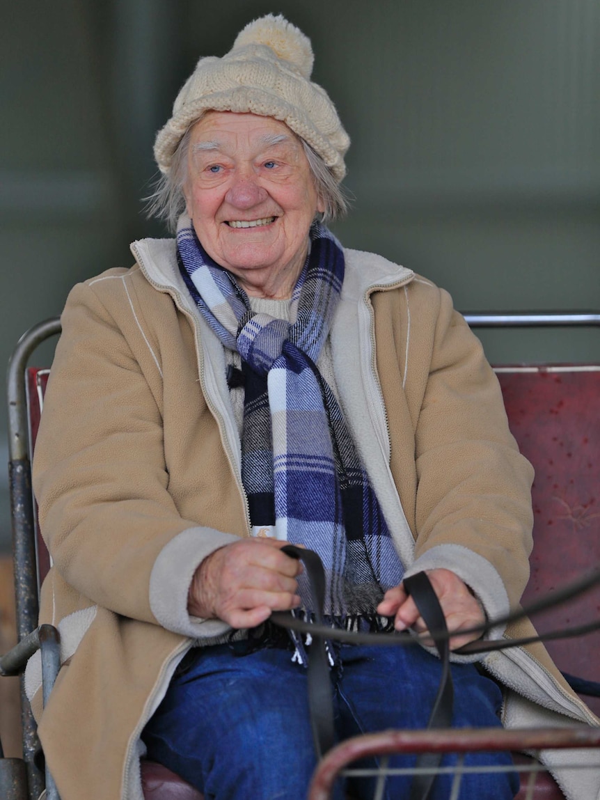 A rugged-up Margaret sits in a cart holding the reigns