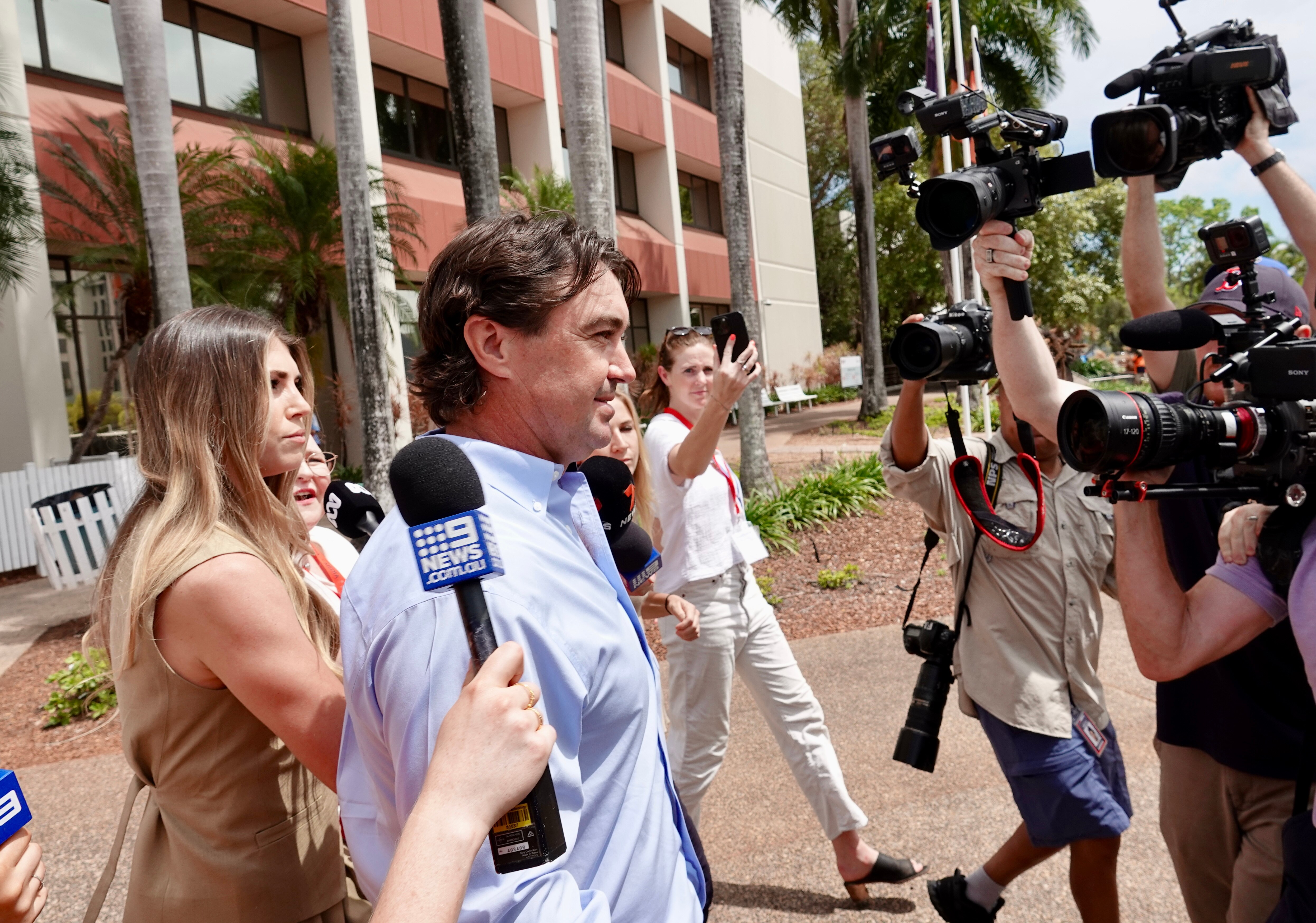 Matt Wright walks while surrounded by people holding cameras and microphones outside the Darwin Local Court.