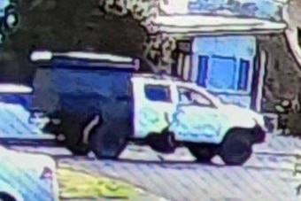A CCTV grainy photo of a white utility on a road.