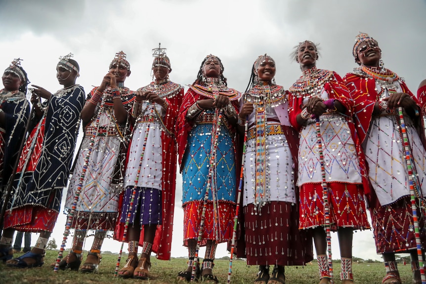 A row of women standing wearing colourful traditional dress.