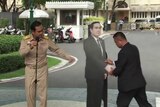 Prayuth Chan-ocha directs an assistant where to place a cardboard cut-out of himself.