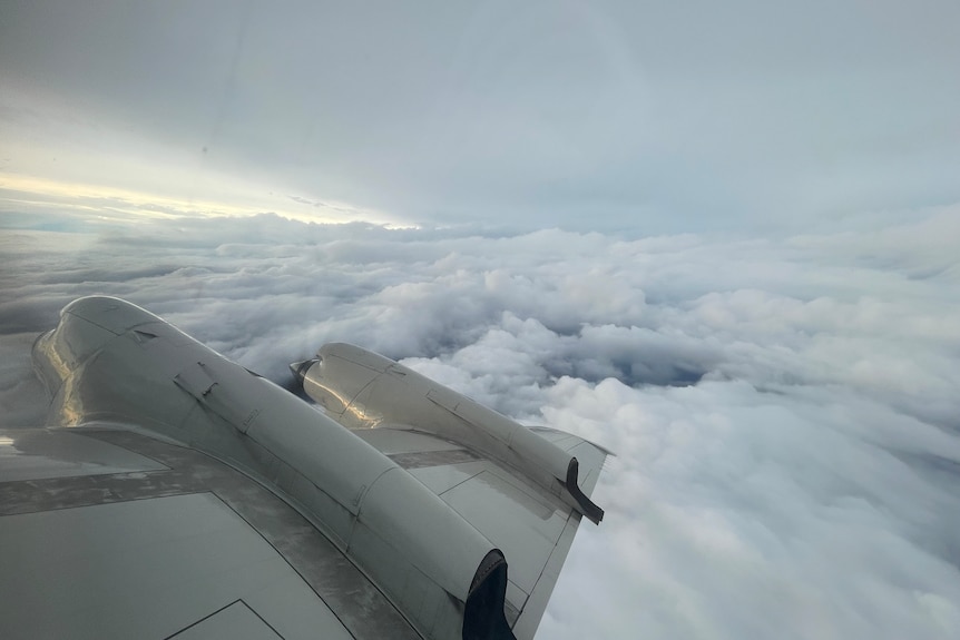 Photo of an aircraft's wing with thick clouds above and below it.