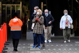 A group of people wearing face masks walk on a footpath