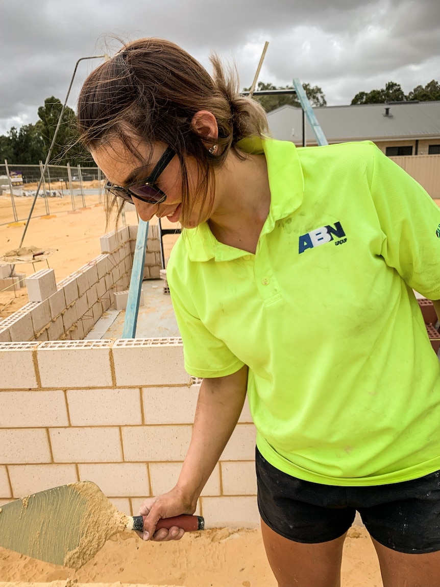 Monique Juratovac holding a cement trowel on a building site