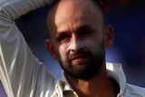 Nathan Lyon stands with one hand on his head and the other on his hip