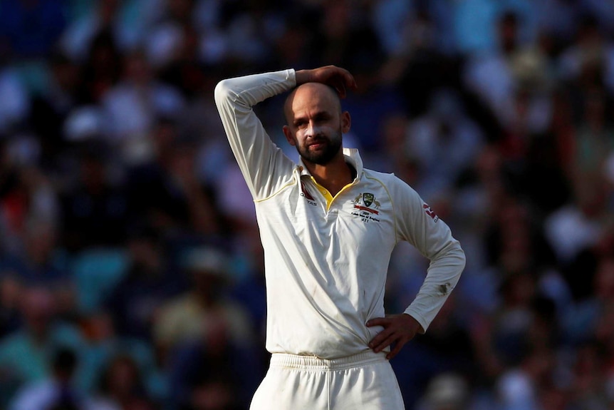 Nathan Lyon stands with one hand on his head and the other on his hip