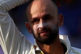 Nathan Lyon stands with one hand on his head and the other on his hip