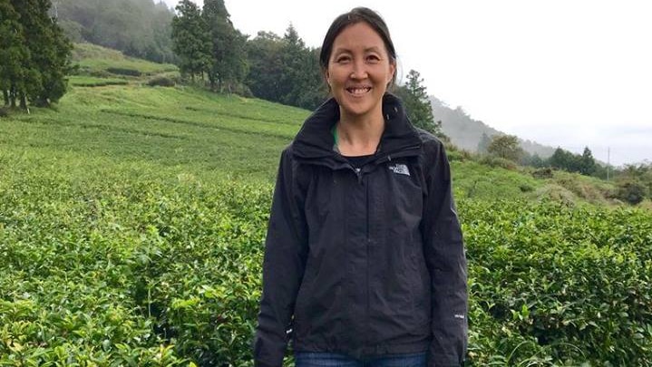 Kym Cooper standing in front of a tea field overseas.