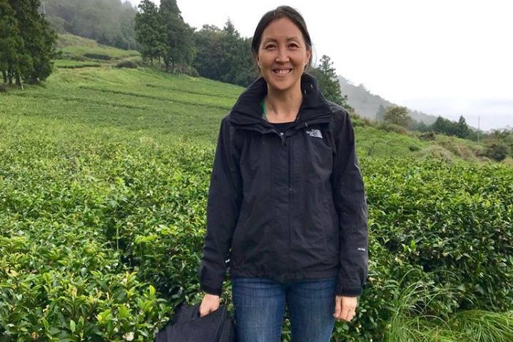 Kym Cooper standing in front of a tea field overseas.