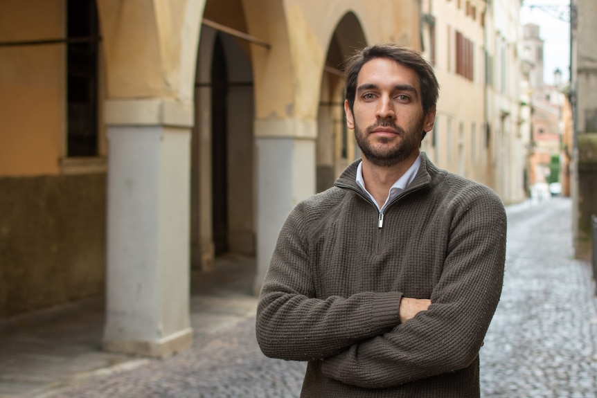 A man with his arms crossed standing in the street