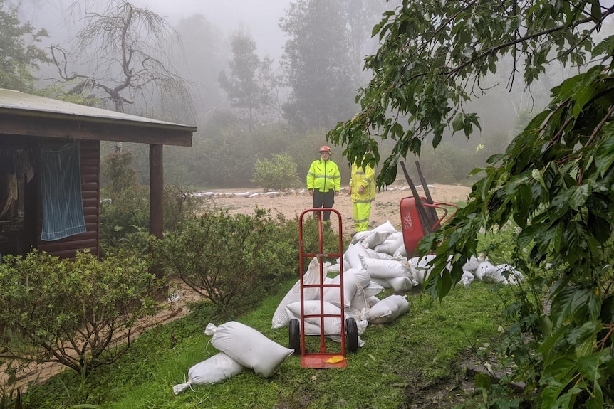 People wearing high-vis vests survey a hill covered with sandbags