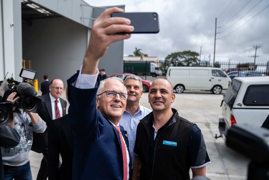 Prime Minister Malcolm Turnbull takes a selfie with workers in Perth.