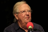 Tim Brooke-Taylor in front of a radio microphone recording an episode of I'm Sorry I Haven't a Clue.