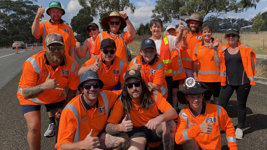 a group of tradies pose next to a highway