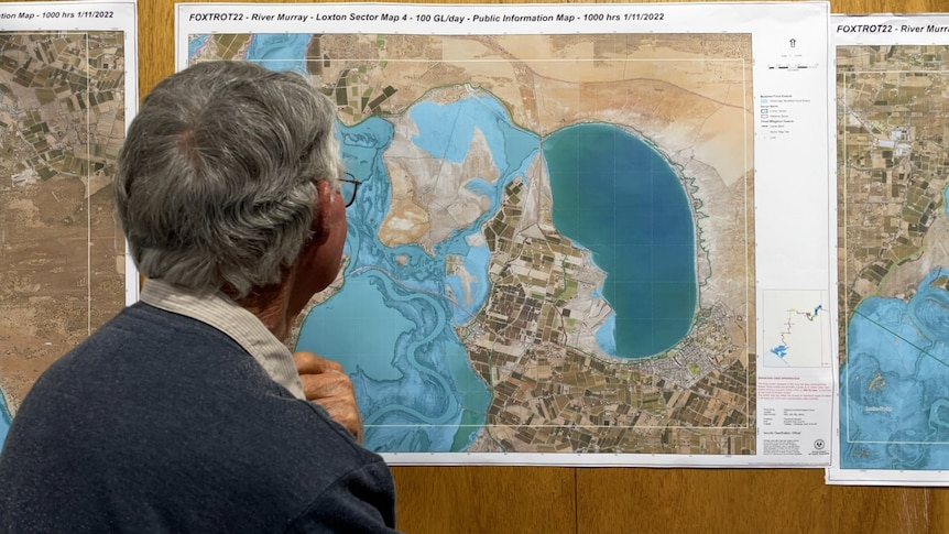 A man looks at a graph showing geography of the river system and a potential flood.