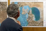 A man looks at a graph showing geography of the river system and a potential flood.