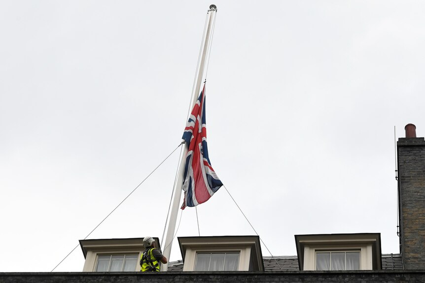 A worker is seen lowering the British Union flag after MP David Amess was killed.