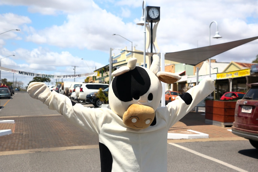 A cow mascot stands in a street.