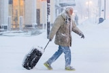 A man moves luggage in snow during a winter storm in Buffalo.