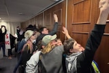 Protesters knocking against a wooden wall