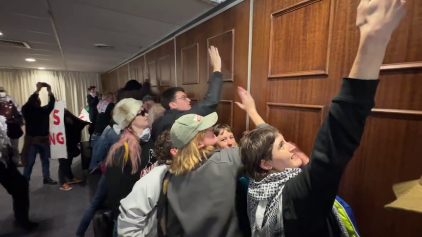 Protesters knocking against a wooden wall