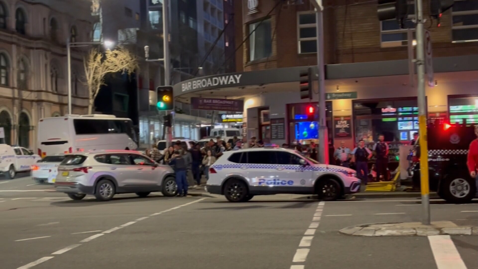 Multiple police cars and officers outside a hotel pub with the sign 'Bar Broadway'.