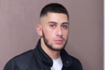 A head and shoulders shot of a Middle Eastern man with dark hair and beard. He has a serious face.