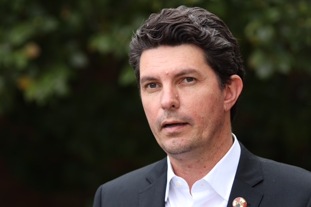 A tight mid shot of WA Greens senator Scott Ludlam speaking outdoors wearing a suit.