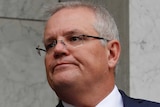Scott Morrison points while speaking in front of a flag