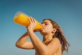 A girl drinks from a bottle of juice