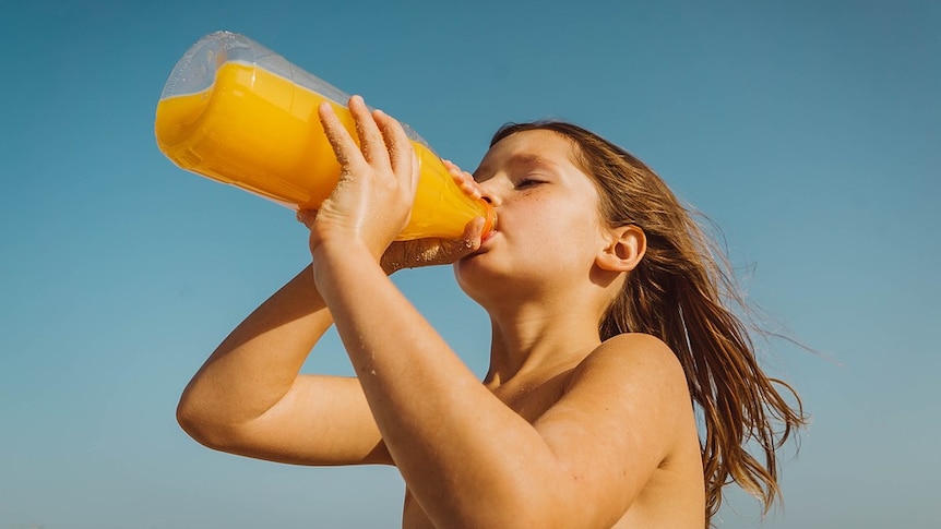A girl drinks from a bottle of juice