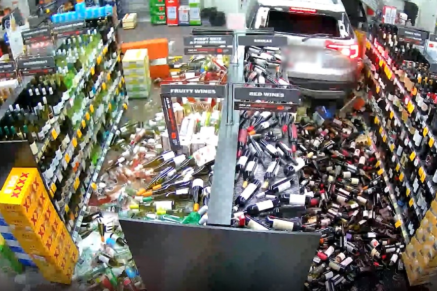 CCTV footages showing an SUV which has backed through a bottle shop window, bottles of alcohol can be seen falling from shelves