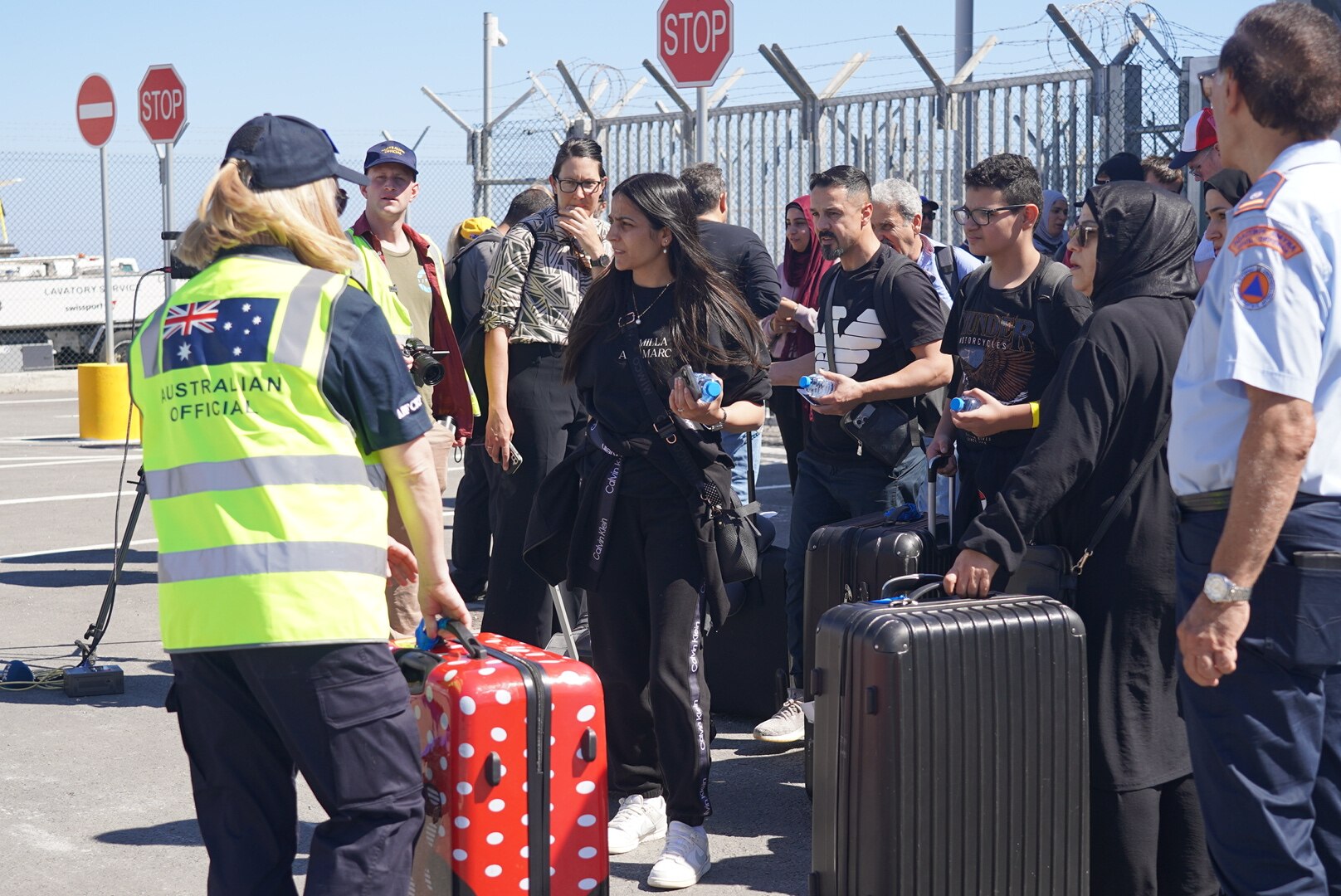 People stand on a tarmac in Cyprus with their luggage