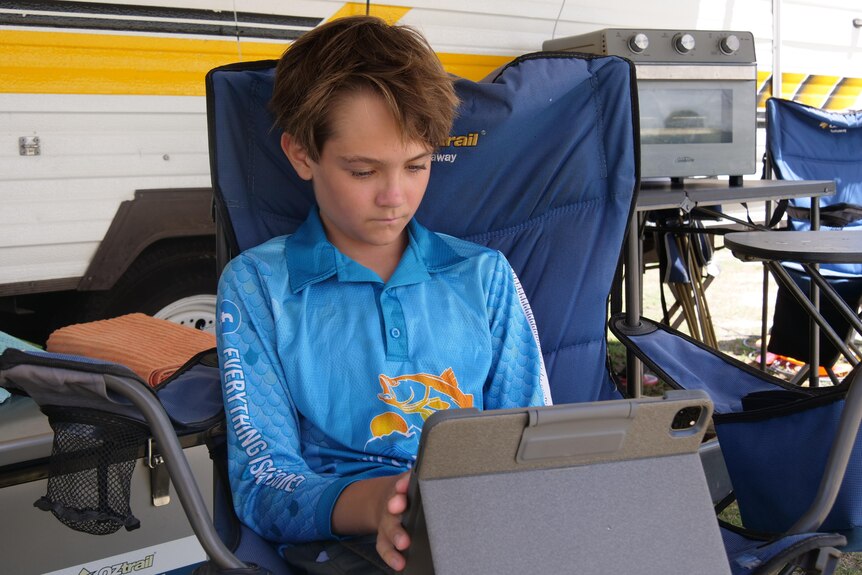 A young boy sits facing a tablet screen