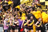 Tigers players celebrate a goal in front of fans covered in the team colours.