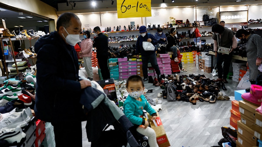 Customers shop at a shoe store during a clearance sale.