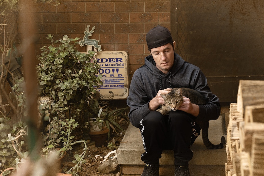 Dion sitting on steps with a cat on his lap