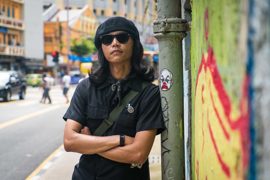 Fahmi Reza leans against a pole with one of his stickers on it.