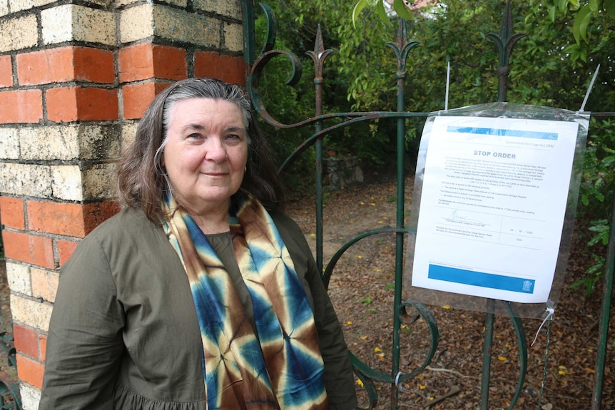 A woman stands next to a gate.