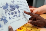 A hand pointing at a page in a book