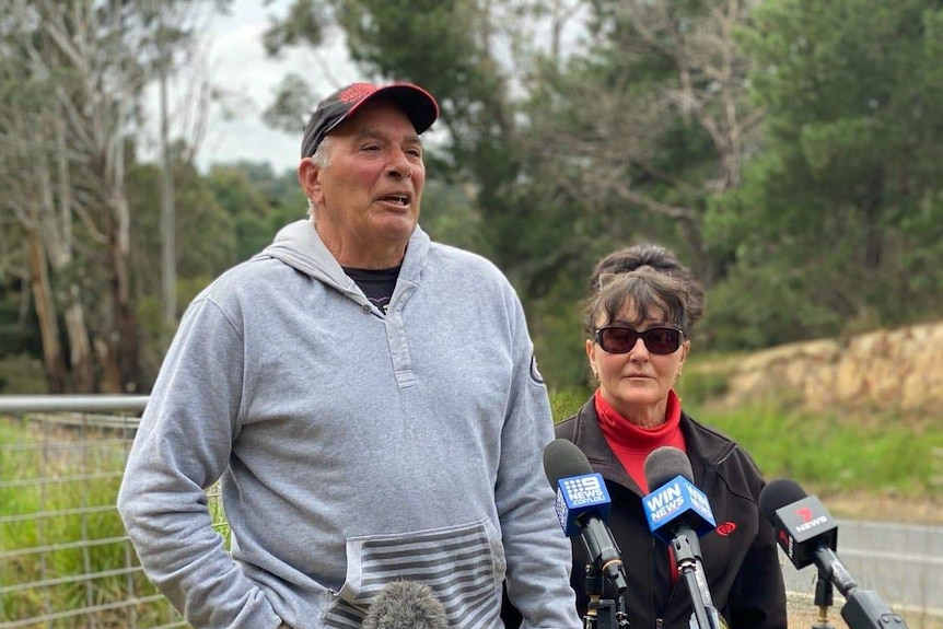 An older couple standing in front of the road where their son was last seen