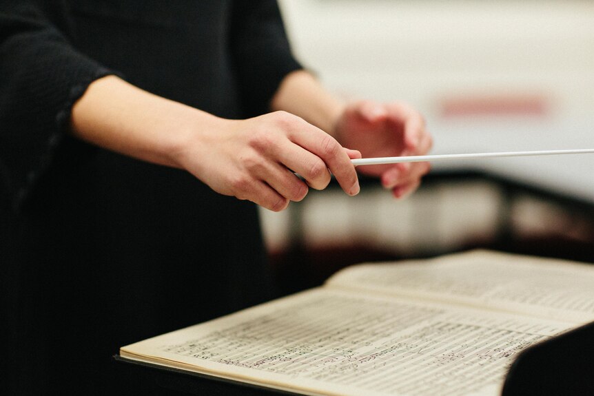 Close up of Nicky Gluch's hand conducting, hovered over a music sheet.