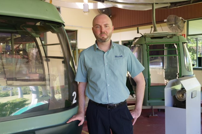 Skyrail cableway general manager Richard Berman-Hardman stands next to cable car.