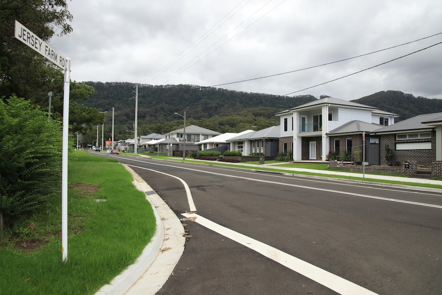 a new road and houses with a hill behind 