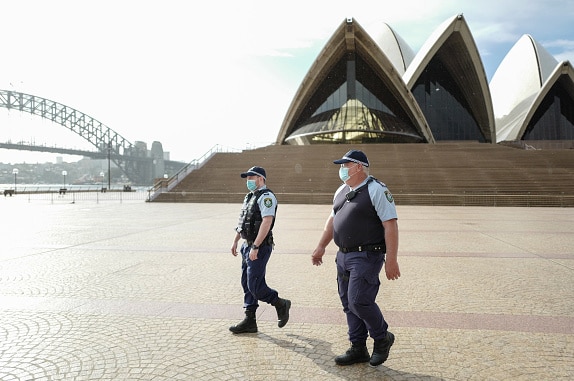 Two police officers walk across from the Sydney Opera House