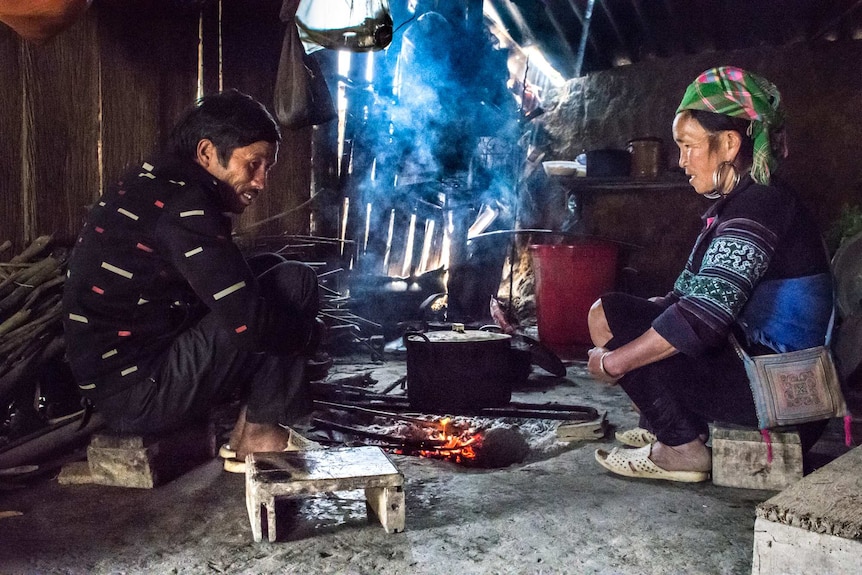 An old Vietnamese couple squat on the floor of their hut