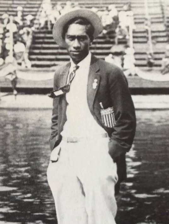 Duke Kahanamoku standing poolside in his USA team blazer