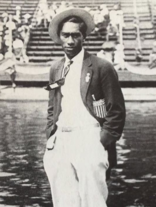 Duke Kahanamoku debout au bord de la piscine dans son blazer de l'équipe américaine