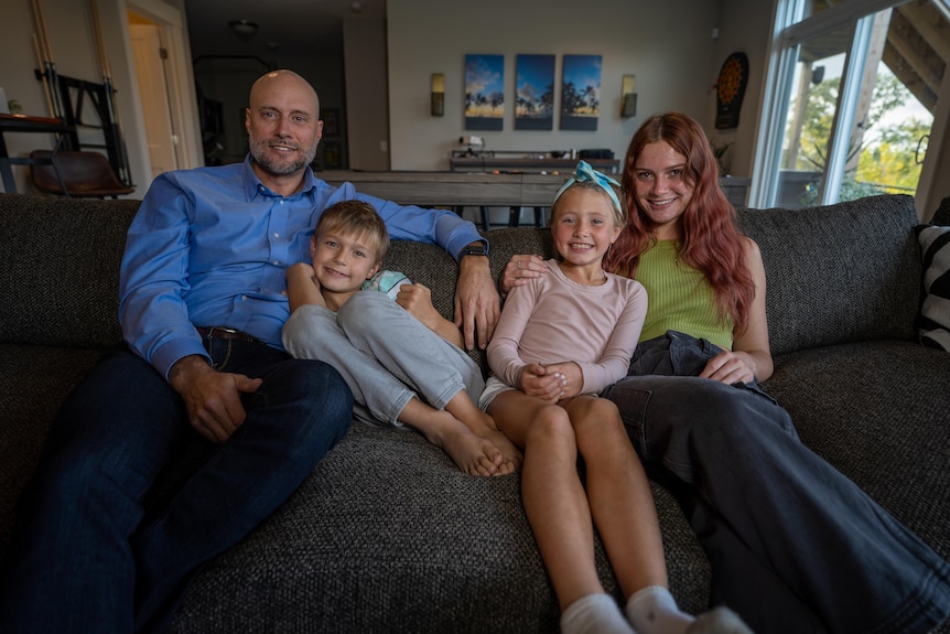 Father sitting with three children on a couch. 