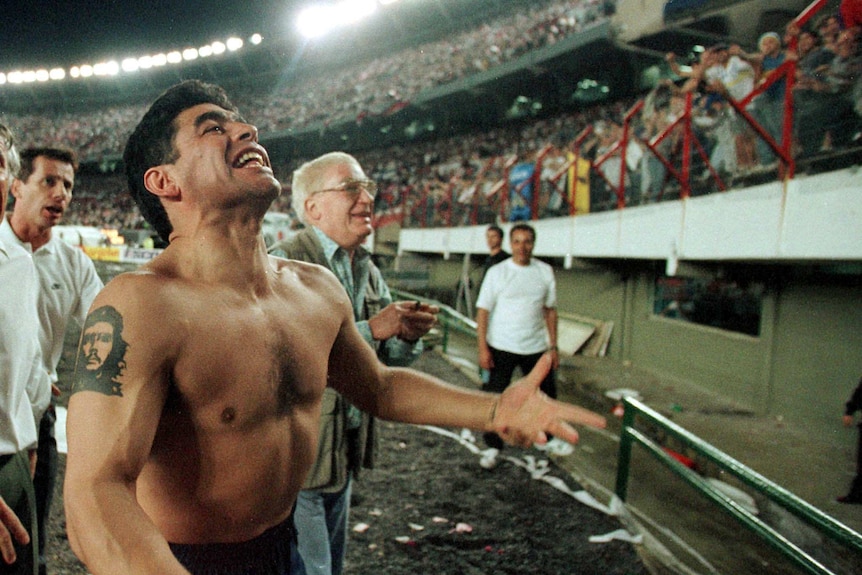 Shirtless Diego Maradona celebrates in front of the stands.